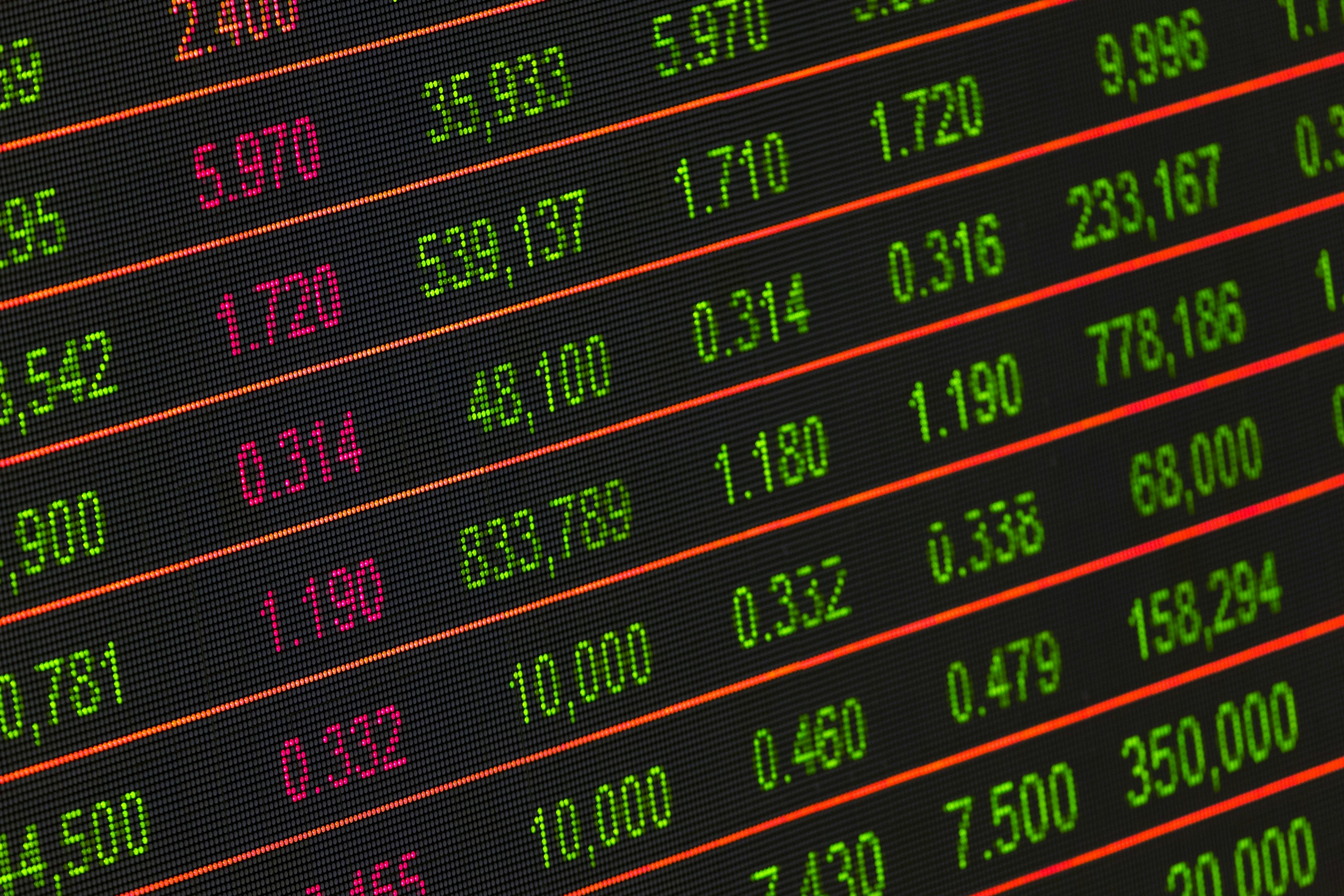 Stock market data with green and red numbers on a digital screen